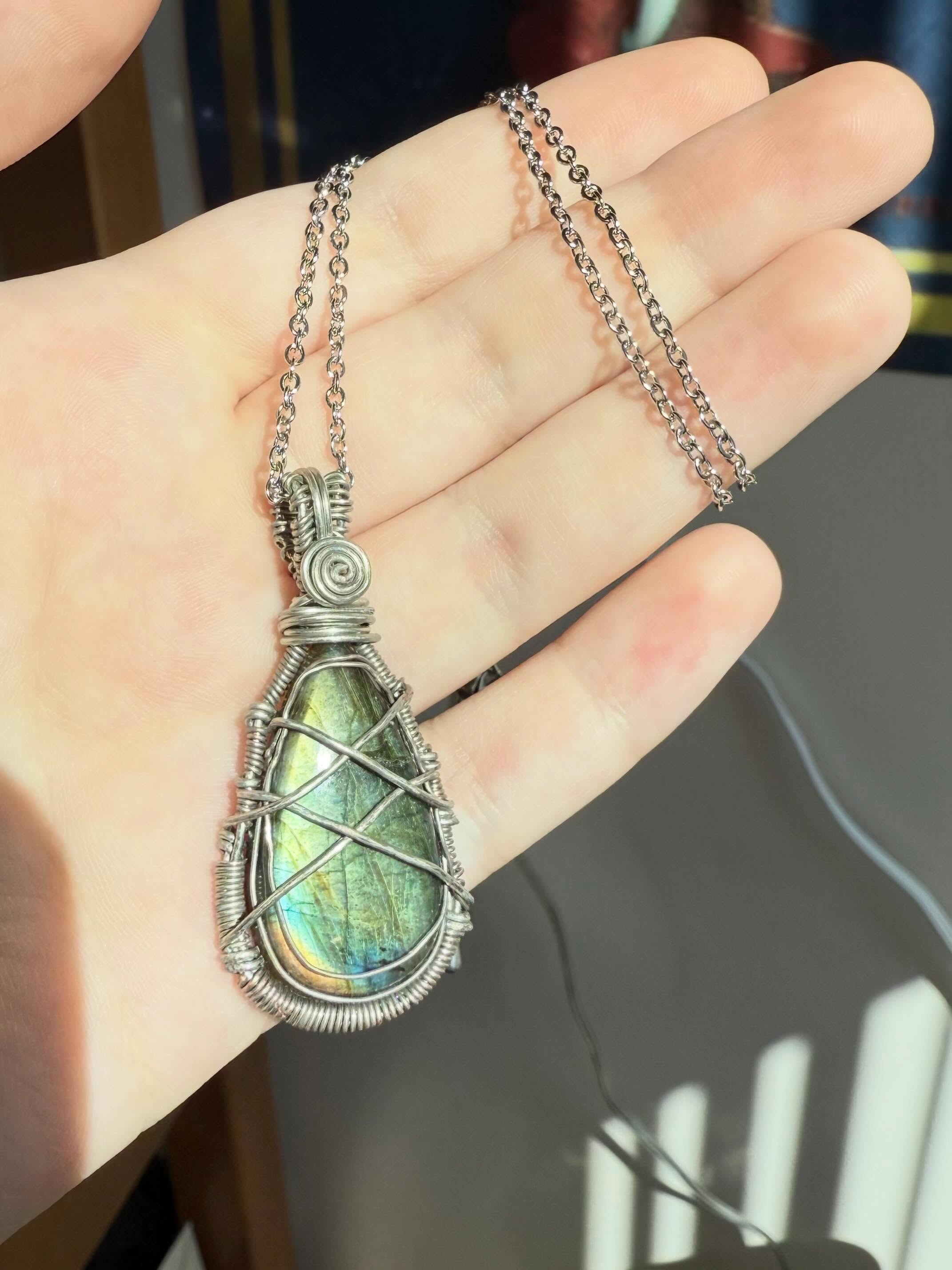 Green wire-wrapped pendant held in sunlight